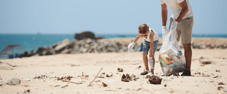 adulto e criança recolhendo lixo em uma praia - Embalixo - fornecedores do Assaí