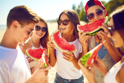 amigos brancos comendo melancia na praia - frutas de verão no Assaí Atacadista - Dia de Hortifrúti