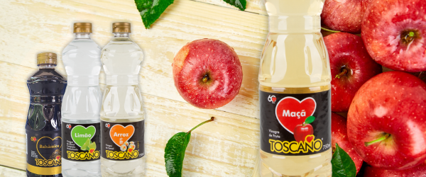 banner com garrafas de vinagre da marca Toscano em um fundo de madeira com uma pilha de maçãs - fornecedores do Assaí Atacadista