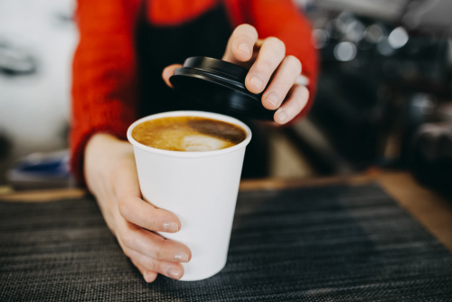 barista tampando um café no copo em uma cafeteria - café pilão e assaí atacadista
