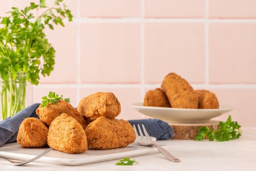 bolinhos de bacalhau na bancada branca de uma cozinha com um ramo de folhas verdes no fundo - presentes de Páscoa - Assaí Atacadista