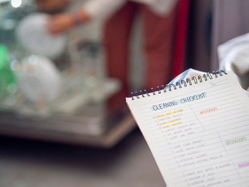 caderno com lista de tarefas para limpeza e fundo desfocado de alguém lavando louça - Assaí Atacadista - limpeza para negócios
