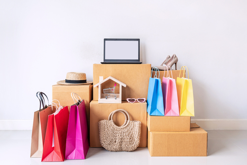 caixas de papelão com sacolas de compras coloridas, um notebook, um chapéu e uma bolsa - Assaí Atacadista - clube de assinatura