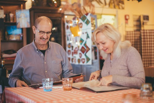 casal branco idoso olhando cardápio - comidas de festa junina - Assaí Atacadista