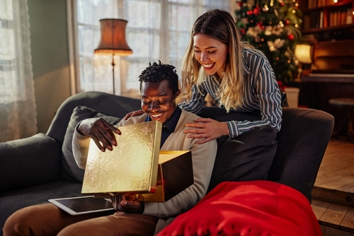 casal interracial com um homem negro abrindo uma caixa de presente de Natal da sua esposa branca - Assaí Atacadista