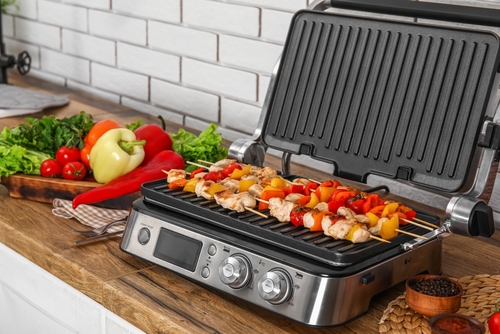 churrasqueira portátil com espetinhos de carne e outros alimentos em uma bancada - eletroportáteis no Assaí Atacadista