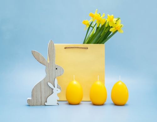 coelhos de madeira, sacola com flores amarelas e três velas em formato de ovo - renda extra na Páscoa - Assaí Atacadista