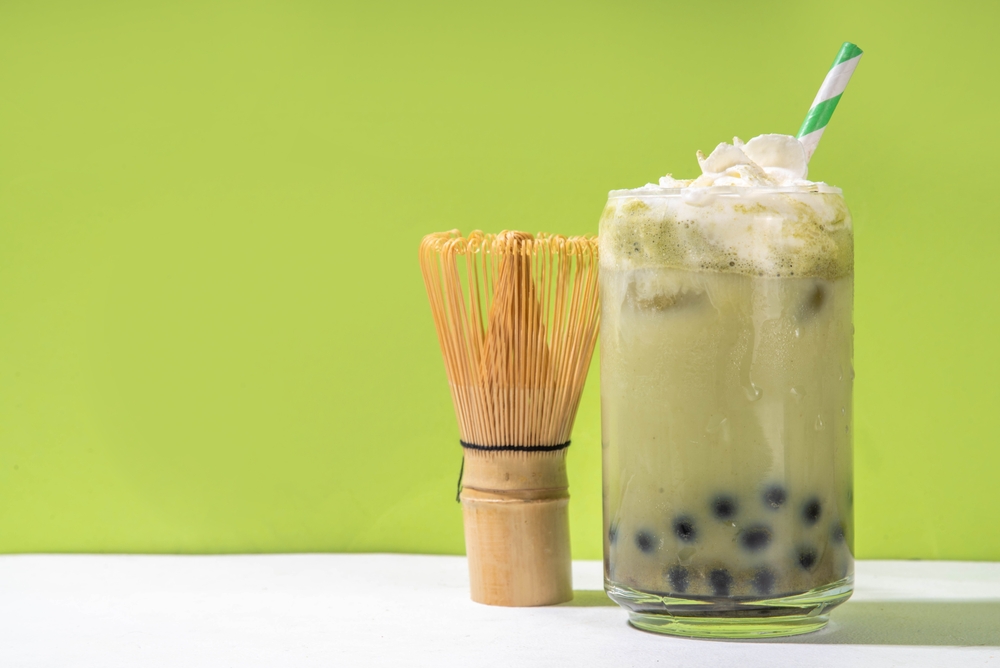 copo com chá matcha gelado com bolinhas pretas e um canudo em um fundo verde - restaurante lucrativo - Assaí Atacadista