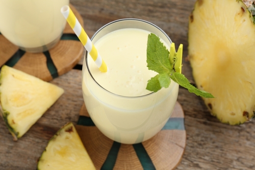 copo com vitamina de abacaxi e uma folha de hortelã com abacaxi em volta - smoothie - Assaí Atacadista - Imagem: Shutterstock