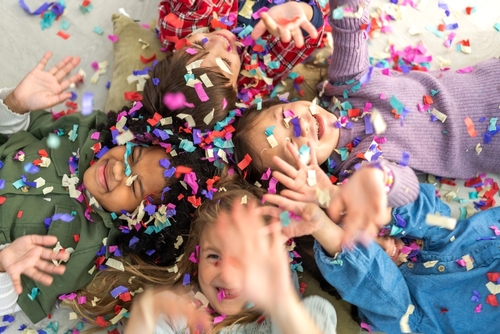 crianças deitadas no chão felizes se divertindo com confetes no rosto - crianças no Carnaval - Assaí Atacadista - Imagem: Shutterstock
