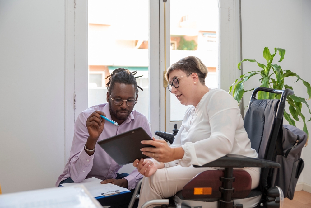 dois colaboradores conversando no trabalho - mulher PCD branca e homem negro - Dia do Trabalhador - Assaí Atacadista