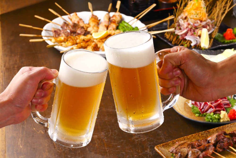 duas mãos brindando com copos grandes de cerveja - bebidas e comidas que combinam - Assaí Atacadista