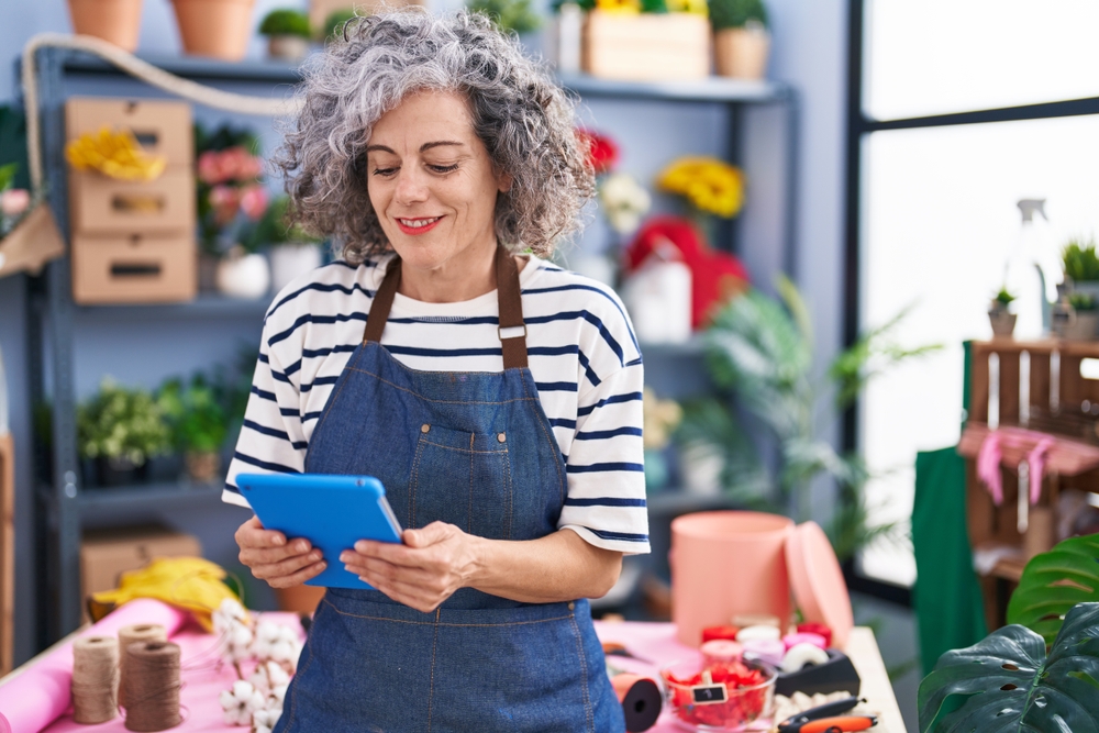 empreendedora mulher branca de terceira idade sorrindo com tablet na mão - networking para comerciantes - Assaí Atacadista