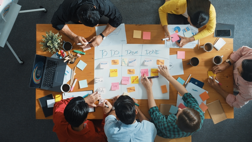 escritório com lista de tarefas em post-its na mesa e pessoas em volta - economia de tempo - Assaí Atacadista