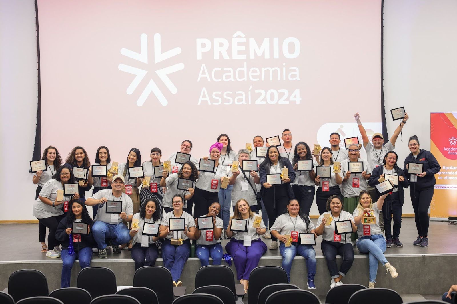foto de pessoas segurando uma lembrancinha e um quadro no palco do Prêmio Academia Assaí 2025 - Instituto Assaí Atacadista