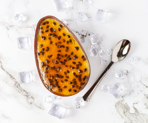 fundo branco com ovo de Páscoa de maracujá e uma colher de chá prateada ao lado - receitas com frutas - Assaí Atacadista