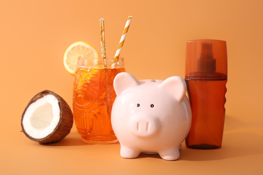 fundo laranja com cofre de porquinho, copo, concha e um protetor solar - dicas de economia para o verão - Assaí Atacadista