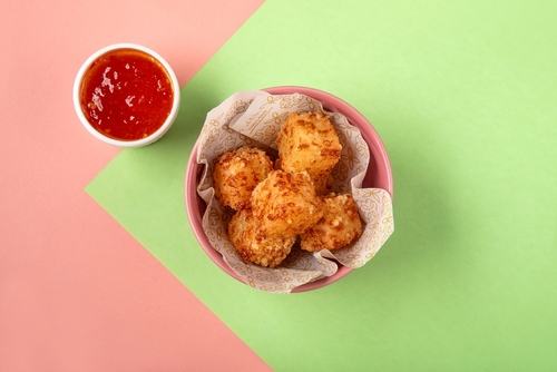 fundo rosa e verde com um pote cheio de dadinhos de tapioca e um pote com molho vermelho - petiscos fáceis - Assaí Atacadista