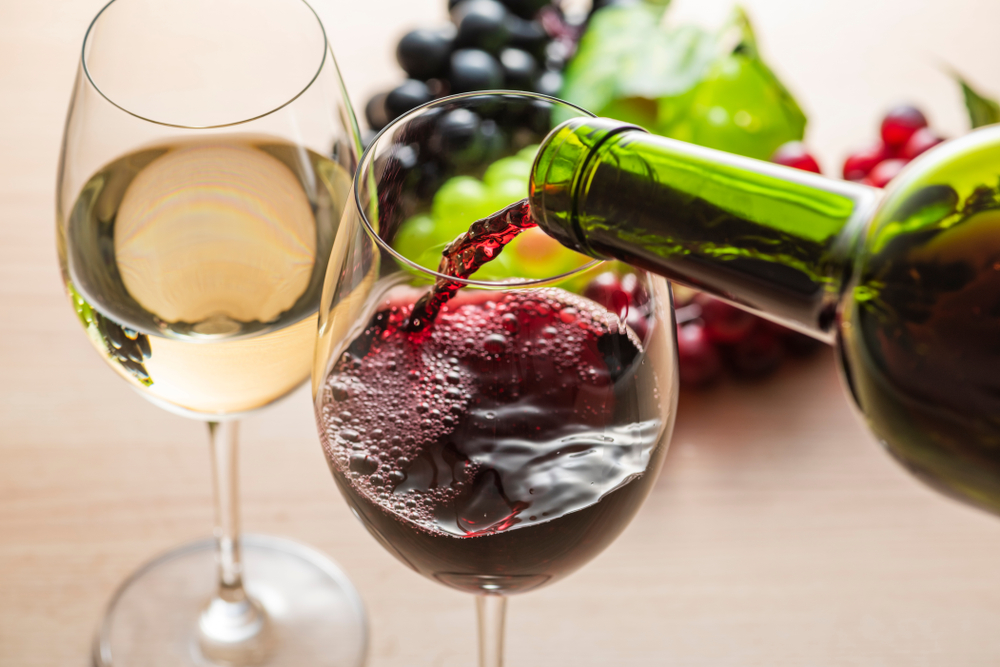 garrafa despejando vinho tinto em uma taça - bebidas e comidas que combinam - Assaí Atacadista