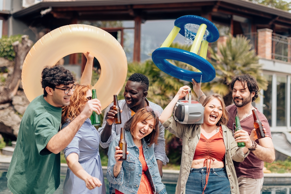 grupo de amigos variados felizes com boias de praia, cervejas e um rádio - descansar nas férias - Assaí Atacadista