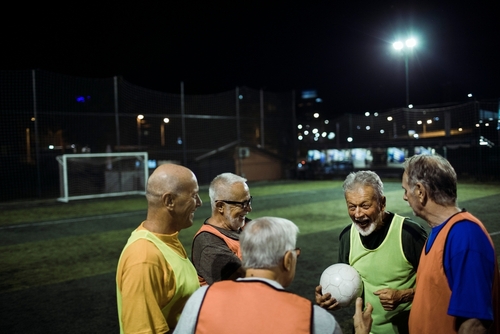 grupo de homens da terceira idade conversando em um campo de futebol à noite - Assaí Atacadista - atividades noturnas - Assaí Atacadista