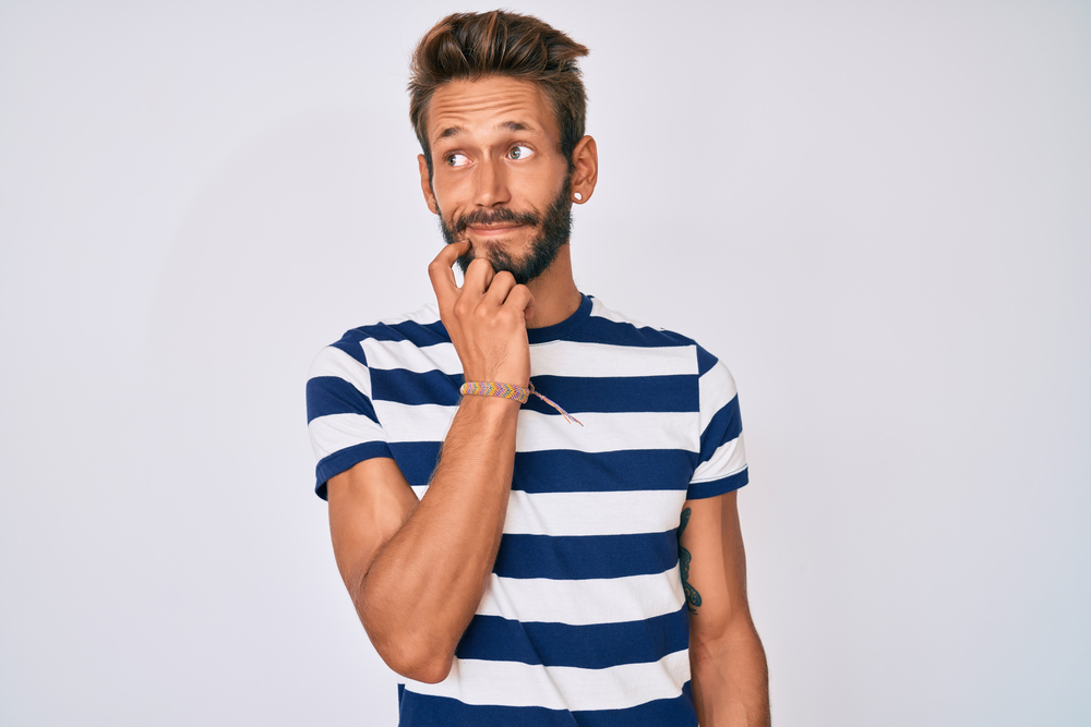 homem branco com uma blusa listrada e expressão de dúvida com a mão no rosto - Assaí Atacadista - FAQ Assaí