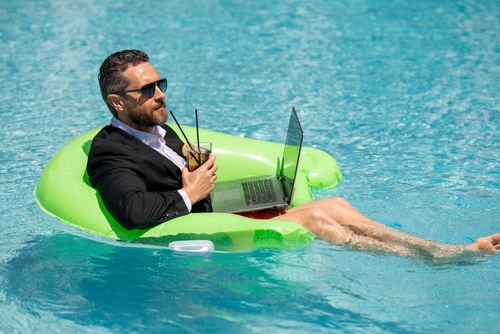 homem branco usando traje social em uma piscina com notebook na boia - Assaí Atacadista - equilíbrio