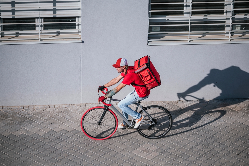 homem branco em uma bicicleta e uma mochila de entrega de comida - lanchonete em casa - Assaí Atacadista
