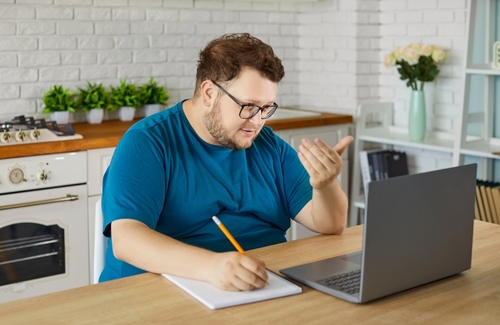 homem branco estudando com um notebook em uma cozinha - Assaí Atacadista - negócio
