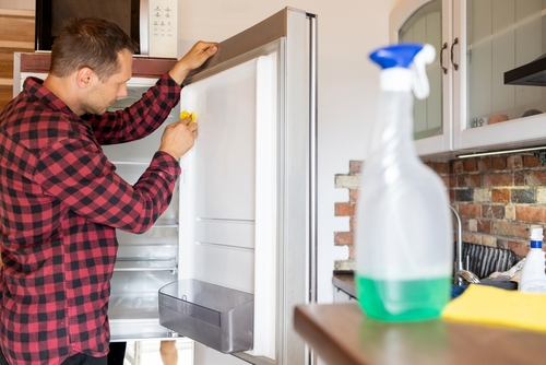 homem branco limpando a geladeira - limpeza da cozinha - Assaí Atacadista