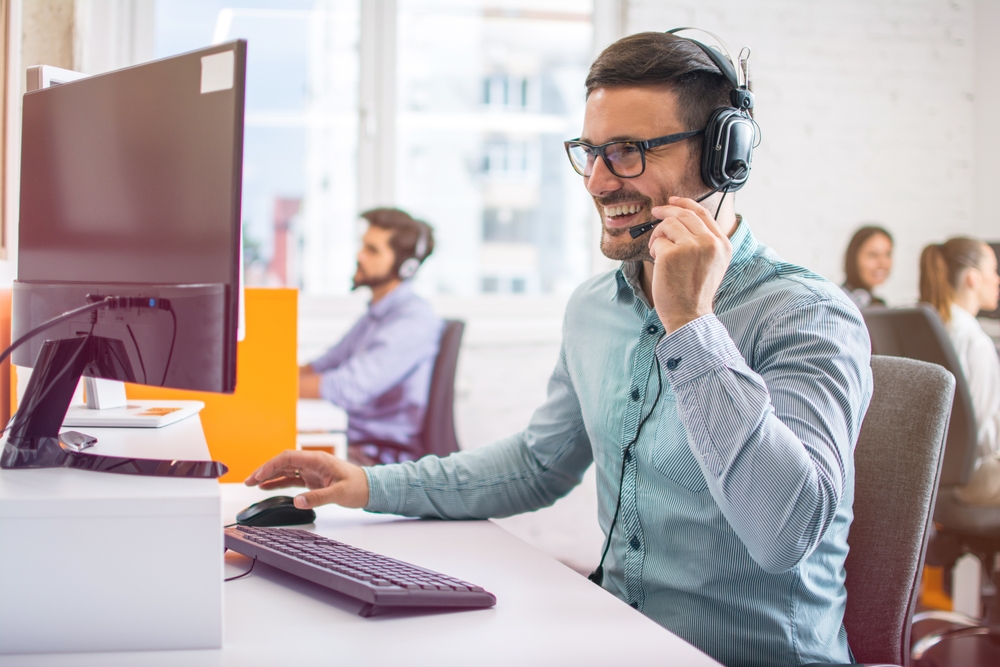 homem branco sorrindo trabalhando com atendimento ao cliente online - Assaí Atacadista