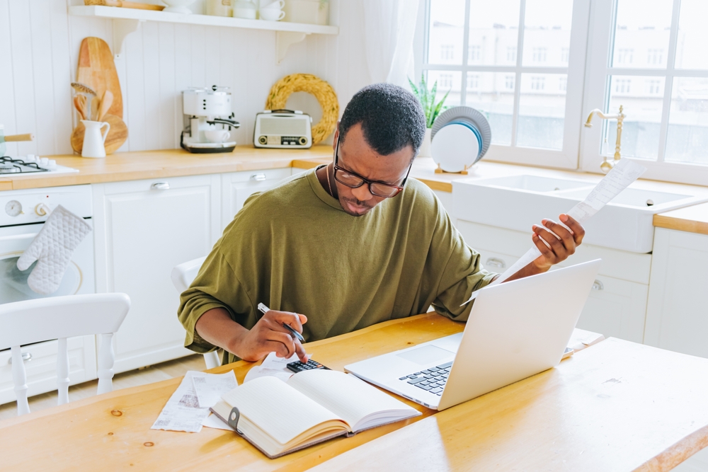 homem negro concentrado anotando finanças - decisões financeiras - Assaí Atacadista