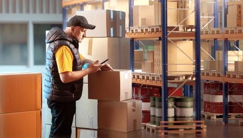 homem olhando para caixas em um estoque logístico-lojas online-Assaí Atacadista