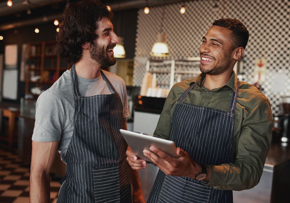 homens funcionários de um café trabalhando sorridentes - Dia do Trabalhador - Assaí Atacadista