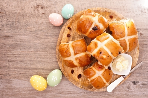 hot cross bun em um prato com ovos de Páscoa coloridos em volta - receita de doces para a Páscoa - Assaí Atacadista