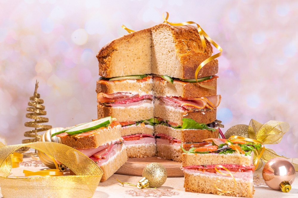 imagem ilustrativa de um panetone salgado com camadas de presunto e queijo, rodeado de decorações natalinas - Assaí Atacadista - panetone artesanal