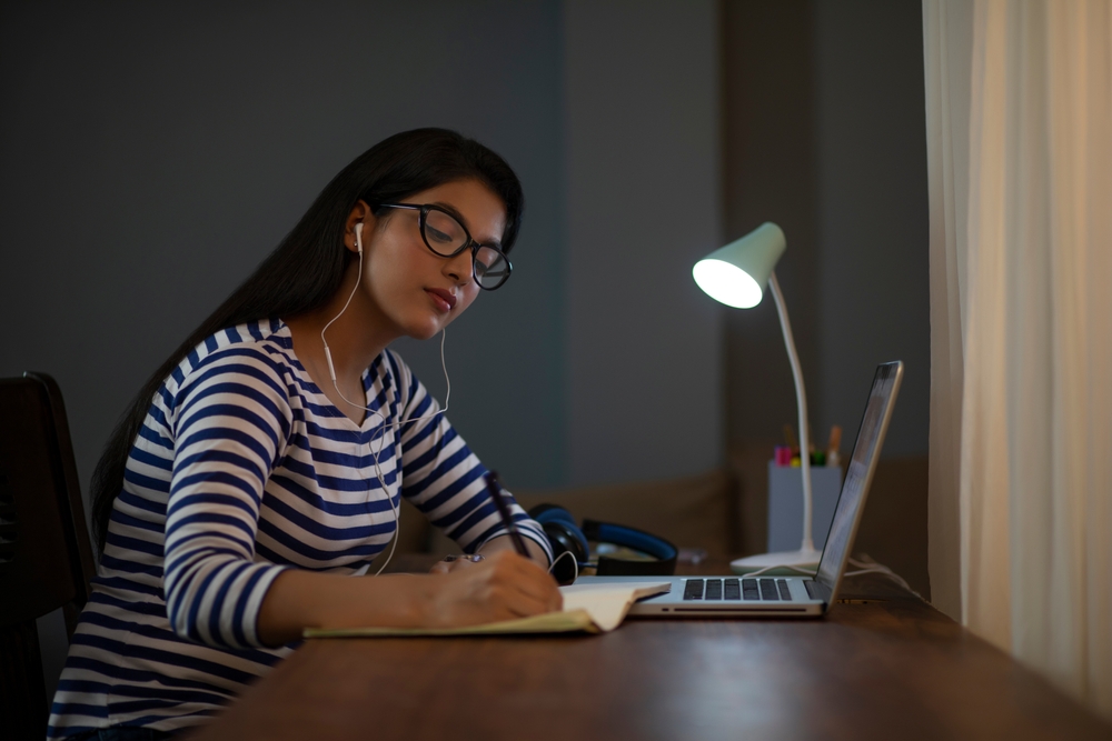 jovem concentrada estudando com um notebook e fone de ouvido - o que fazer no verão - Assaí Atacadista