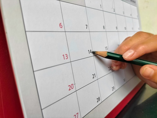 mão segurando um lápis apontando para uma data em um calendário - lista de compras - Assaí Atacadista
