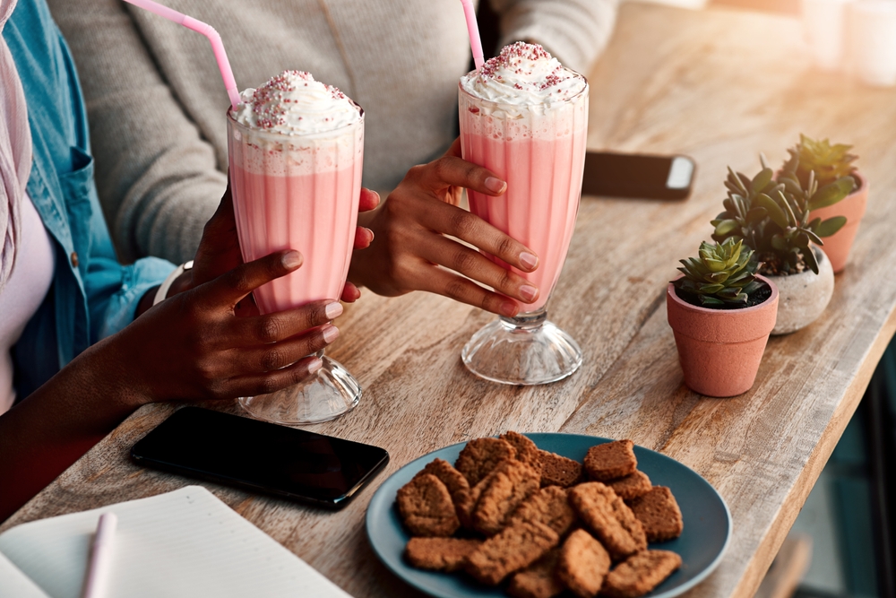 mãos de pessoas negras segurando copos com milkshake rosa - renda extra no verão - Assaí Atacadista