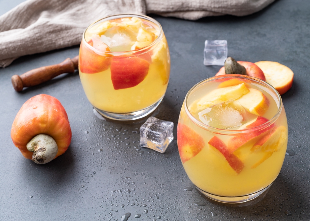 mesa com dois cajus acompanhados de dois copos com uma bebida de caju e gelo - drinks de Natal - Assaí Atacadista