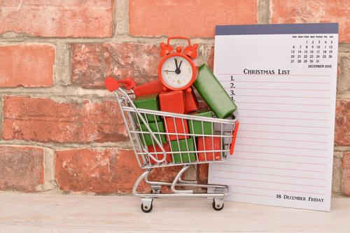 mini carrinho de compras com caixas e um relógio dentro apoiado em um bloco de anotações-Assaí Atacadista-compras de fim de ano