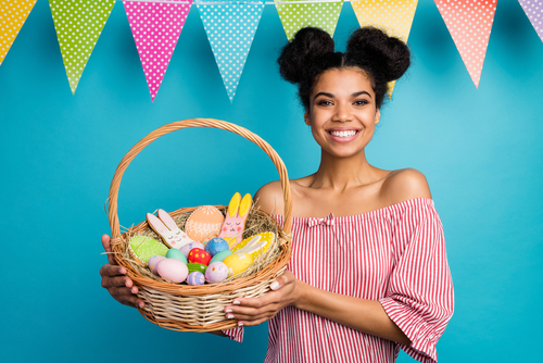 mulher feliz segurando uma cesta com doces e chocolates - presentes para o Dia da Mulher na Páscoa