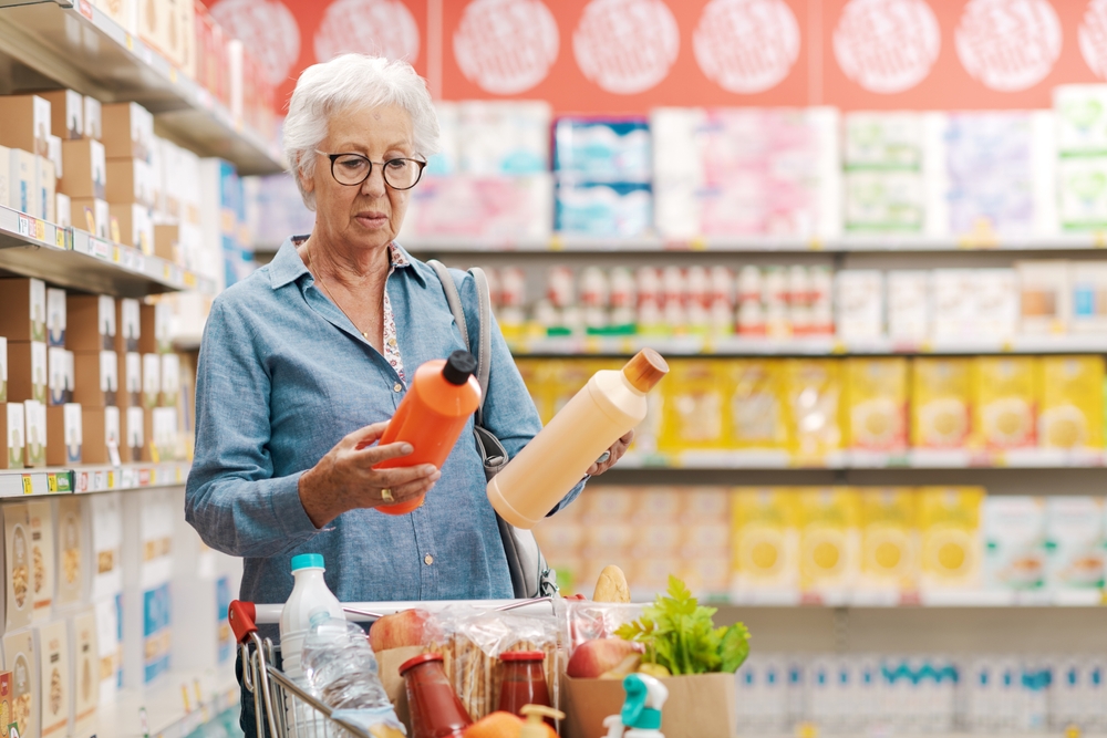 mulher idosa fazendo compras com dois produtos nas mãos - economizar nas compras - Assaí Atacadista