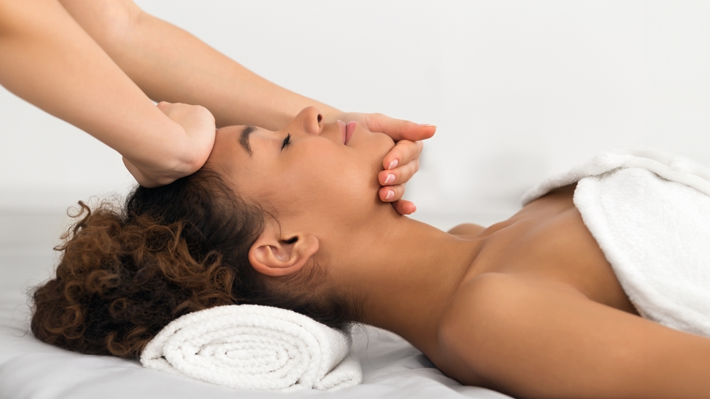 mulher negra relaxando com uma massagem facial - autocuidado para mães - Assaí Atacadista