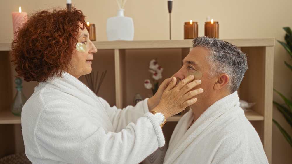 mulher segurando rosto de homem fazendo skincare com roupão - o que fazer no verão - Assaí Atacadista