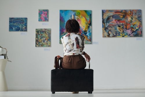 mulher sentada em um museu vendo quadros - Assaí Atacadista - aniversário sem festa