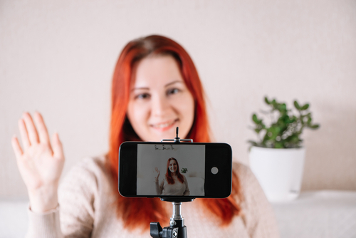  mulher sorrindo acenando para a câmera do celular em um tripé - crianças na Páscoa - Assaí Atacadista