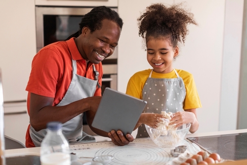 pai e filha de uma família negra cozinhando juntos - aniversário em casa - Assaí Atacadista