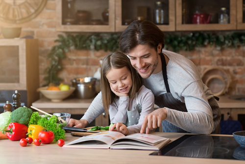 pai e filha lendo um livro de receitas na cozinha - assaí atacadista