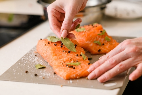 pessoa branca temperando peixe salmão para a pascoa - assai atacadista